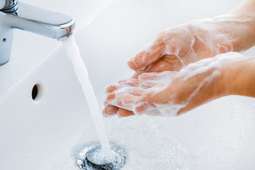 Fototapeta premium Woman use soap and washing hands under the water tap. Hygiene concept hand detail.
