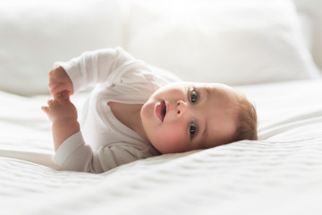 Cute happy 7 month baby girl lying on bed