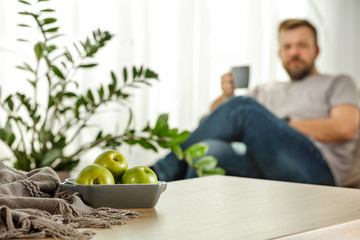 Fototapeta premium Board of free space with green apples.Home interior with man and sunny morning light. 