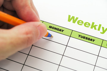 Person writing weekly schedule with ballpoint pen - Powered by Adobe