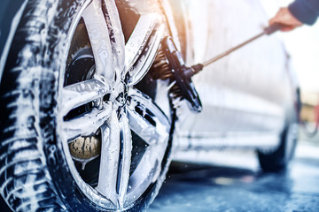 Car wheel wash. Car cleaning with water jet. Car rim or aloy washing close up. - obrazy, fototapety, plakaty