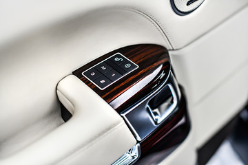 Car interior details of door handle with window control buttons and adjustments. Luxury close up or car window controls system.