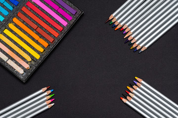 pastel crayons for drawing in a black box and color pencils for drawing on a black background