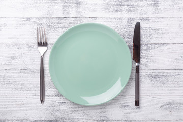 Empty green mint plate and cutlery on wooden background. Copy space. Top view