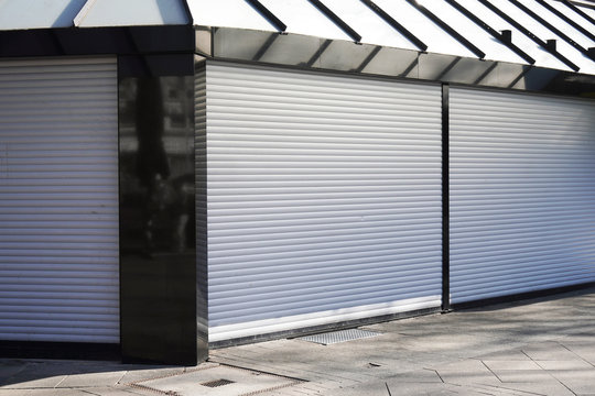 closed business shop or store front with roller shutters - economy crisis and recession concept