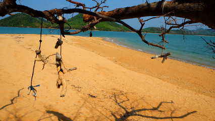 Coral hanging mobile on tree with island view background.