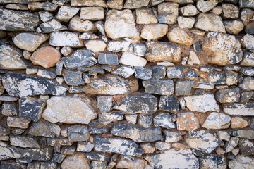 Natural stone wall for backdrop texture, white grey beige color, wallpaper. Vintage strong stone block wall of many shapes and sizes.