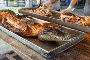 Whole skinless roasted crocodile on a metal baking sheet
