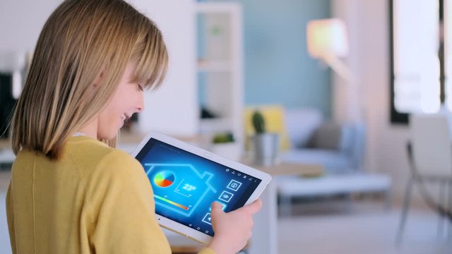 Video of little girl using a domotic system with her digital tablet while standing at home.