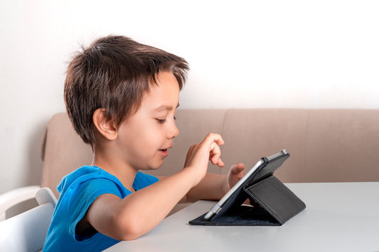 Little boy browses the internrt on a  tablet. Modern lifestyle.