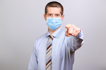 A man in a light shirt, tie and medical mask pokes his finger into a cell isolated