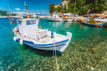 Traditional fishing boat in crystal clear Mediterranean sea cove of Ithaka island, Greece - obrazy, fototapety, plakaty