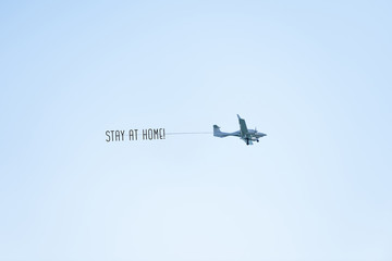 Airplane with STAY HOME text or message to citizens (people) of the country and the world flying in the blue sky. protect from chinese Coronavirus or Covid-19 epidemic. Quarantine.