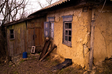 Fototapeta na wymiar Old ruined village house. Abandoned rural yard. Window frame, broken glass, peeling paint.
