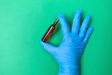 vaccine bottle in hands on a green background. Coronovirus Theme