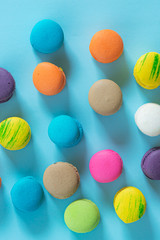 Colorful cake macaron or macaroon on turquoise pastel background from above. French almond cookies on dessert top view
