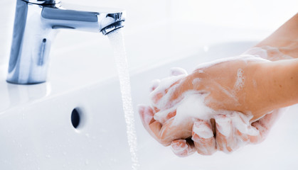 Woman use soap and washing hands under the water tap. Hygiene concept hand detail.
