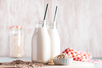 Non dairy oat milk in glass jars with reusable metal straws. Healthy vegan milk alternative still life, copy space. Substitute for traditional cow milk with oat flakes, healthy lifestyle concept