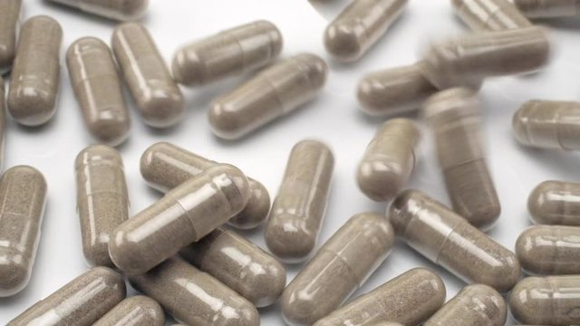 Close Up View of Natural Herbs Capsules Falling and Bouncing on White Background.