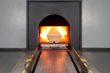 Ein Sarg wird in einem Krematorium zur Feuerbestattung in den Ofen geschoben, die Flammen haben ihn bereits erfasst und die Ein&auml;scherung hat begonnen