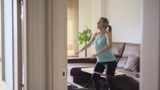 woman doing exercises with an elastic band in the living room at home. Healthy life concept