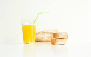 a glass of yellow juice on a white background and slices of white bread