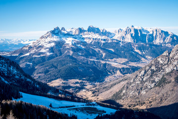 Fototapeta na wymiar Sunny winter landscape at Ski Area in Dolomites, Italy - Alpe Lusia. Ski resort in val di Fassa near Moena. Winter Dolomites and blue sky. Aerial view on ski slopes