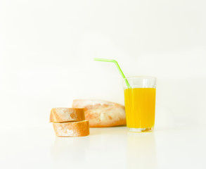 a glass of yellow juice on a white background and slices of white bread