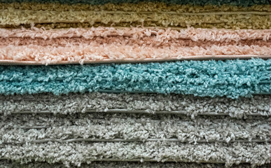 Carpets of various colors stacked in a warehouse.