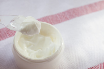 Cream in a cosmetic spoon close-up on the background of a cotton tablecloth. Spa concept, beauty salon. Minimalism.