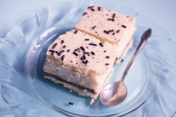 Two slices of homemade cakes decorated with chocolate crumbs on a blue background