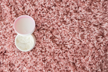  Wrinkle cream in a white jar on a pink fluffy bedspread. home skin care for the face and body.