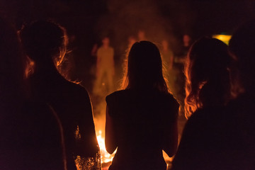   A lot of people around the fire at night at the festival.