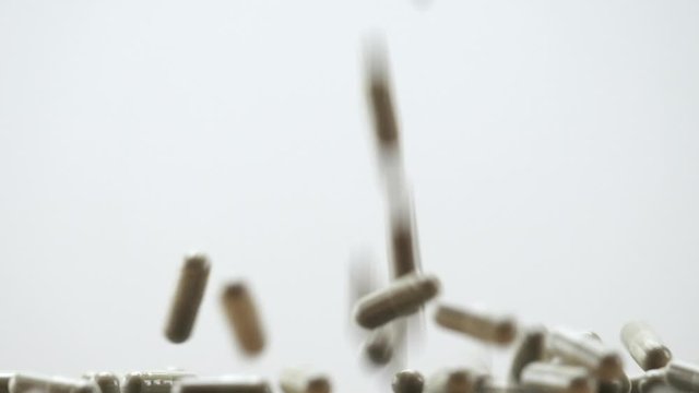 Close Up View of Natural Herbs Capsules Falling and Bouncing on White Background.