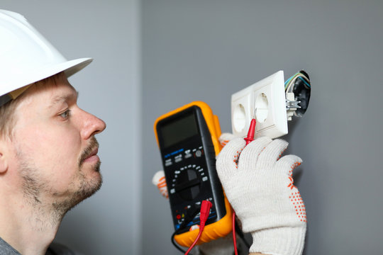 Electrician in helmet measures level electricity