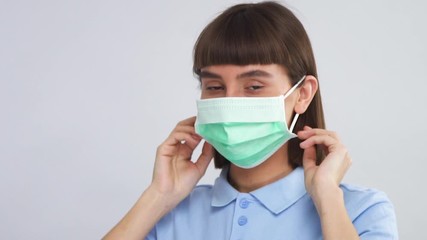 lovely teenage girl putns on sterile medical mask and showing thumbs up to camera