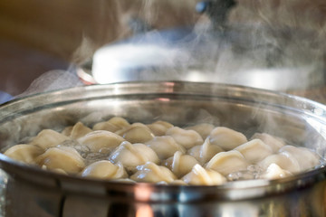 dumplings are cooked in a pot. Cooking in the kitchen. Steam from the pot.