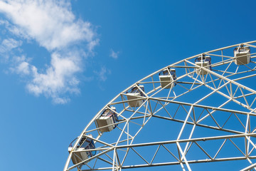 Bottom view of part white ferris wheel on background of blue sky and cloud in sunny day.