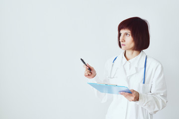 Female adult doctor stands on white background фтв shows, makes a hand gesture