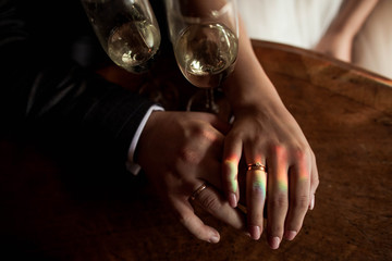 hands of wife and housband with glass of wine and rainbow