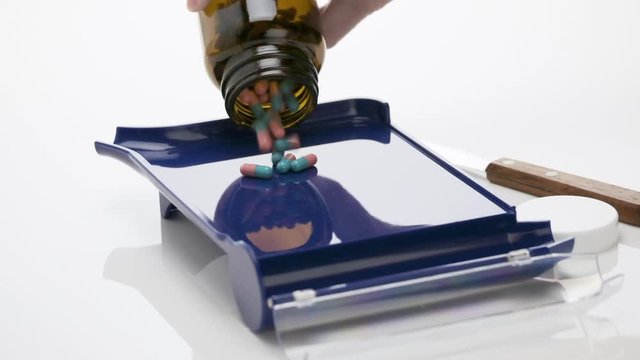 Slow Motion of Blue Teal and Pink Colored Capsules Falling from Bottle on Pharmacist Blue Counting Pills Tray