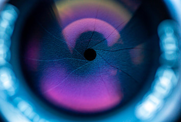 Beautiful objective lens of photo camera with purple light on glass close up. Background pattern