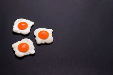 Three jelly fried eggs on the left on a black background, close-up shot. Sweet photo for your delicious design.