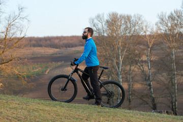 Cyclist in pants and fleece jacket on a modern carbon hardtail bike with an air suspension fork. The guy on the top of the hill rides a bike.