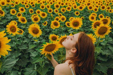 Portrait of a beautiful, cute, sexy red-haired girl in a white dress with sunflower flowers. Emotion of pleasure, freedom concept, lifestyle.