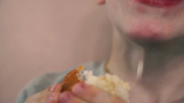 Closeup child happily eating a sandwich, picking up crumbs of food from his lips, smiling