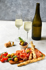 Traditional Italian appetizers ( antipasto ) : salami, bresaola, prosciutto, olives. Aperitif in Italy in Florence, Rome, aperitif in Milan. Two glasses of Prosecco and sticks of cereal bread