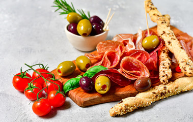 Traditional Italian appetizers antipasto : salami, bresaola, prosciutto parma, olives. Aperitif in Italy in Florence, Rome, aperitif in Milan. Two glasses of Prosecco and sticks of cereal bread