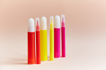 Colored markers thin thick red yellow pink light background. Rainbow-colored stationery is on the table.