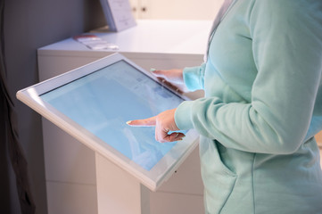 Faceless woman touching the screen of a self-service device in a store. Device store navigator....